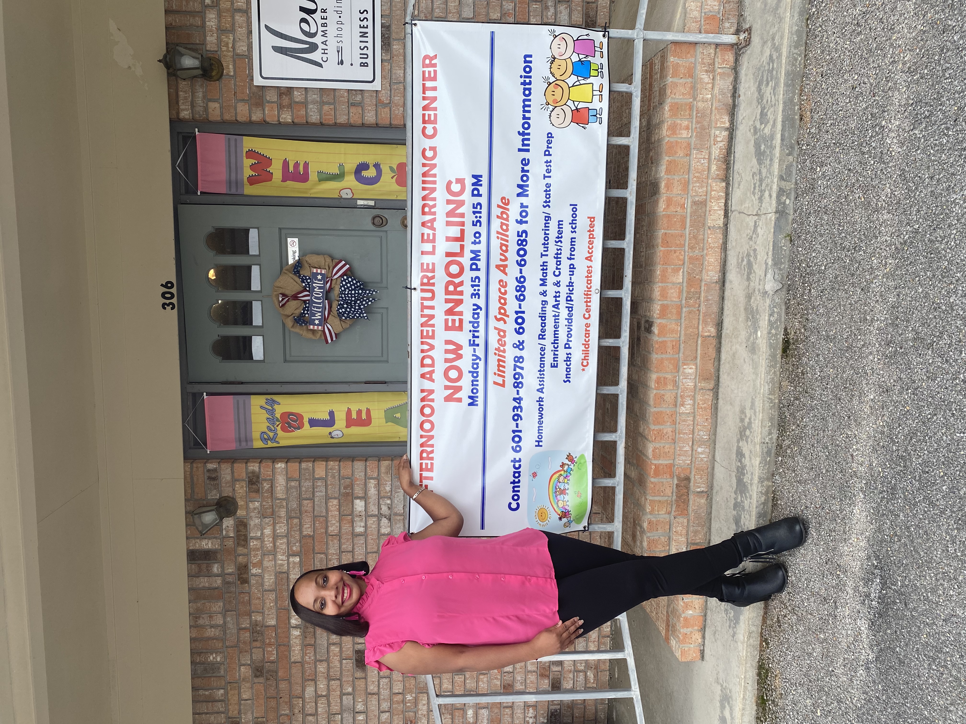 Afternoon Adventure owner standing beside enrollment banner